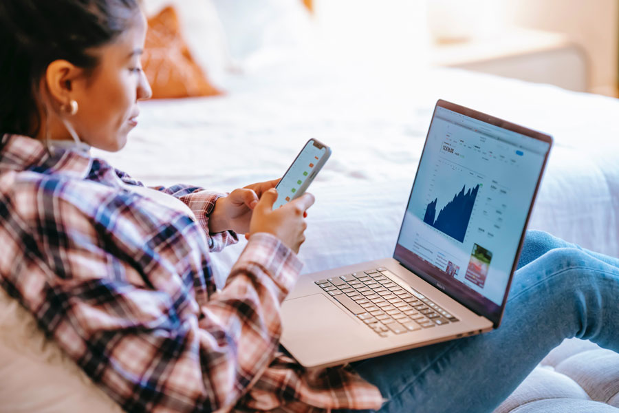 Female works on computer and phone looking over data