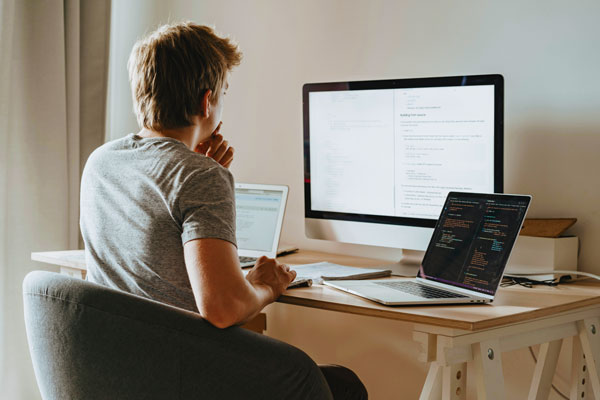 Male Data Science student working at desk with multiple computers