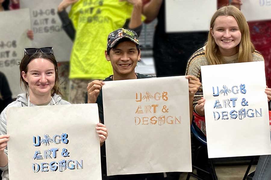 Three students hold up design type project