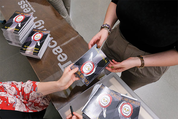 Author handing a signed book to their reader.