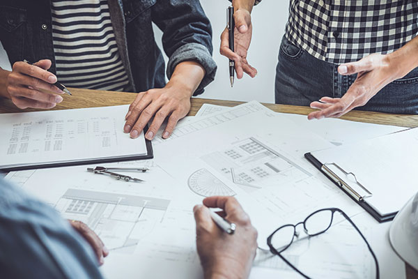 People around a table with house map designs.