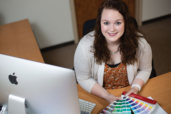 Kady Jordan sitting and showing several color palettes.