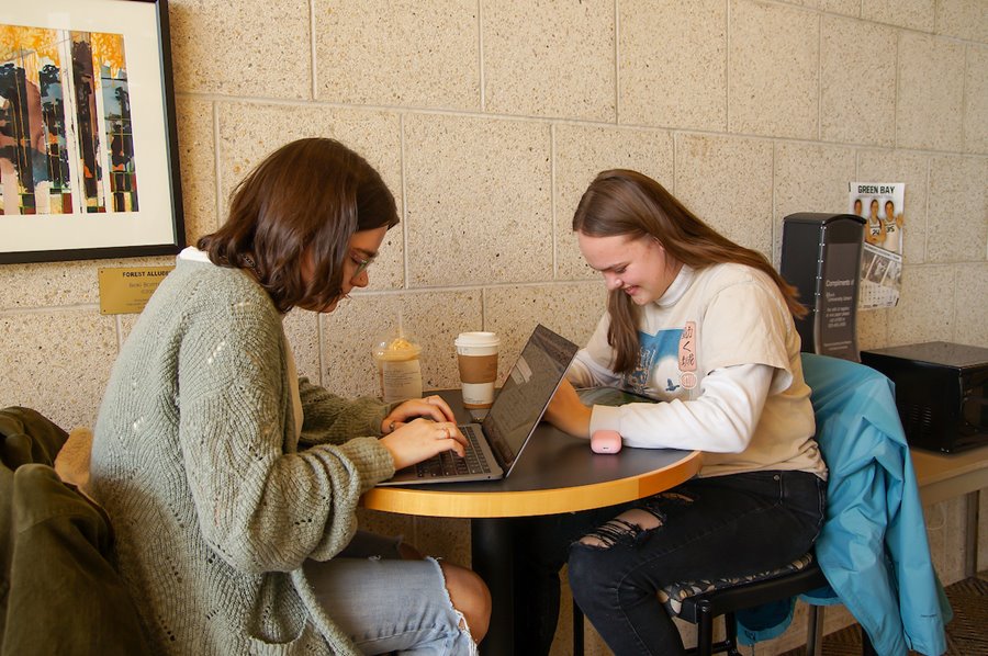 Two students having coffee while working on lap tops