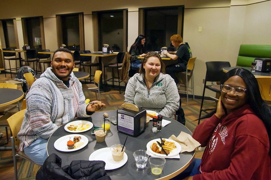Three students sit around a table and enjoy Late Night Breakfast