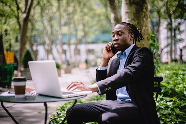 Writer works on laptop outside while talking on the phone