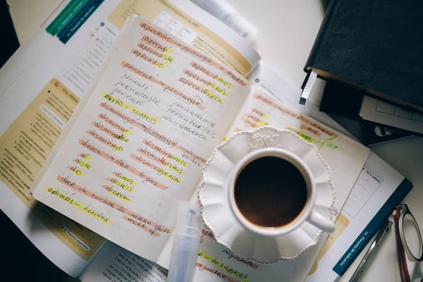 Notebook with highlighted spanish verb conjugation and coffee