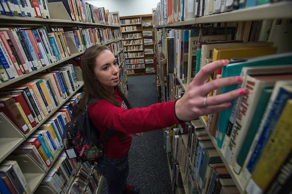 Student in the UWGB Marinette Campus Library takes a book off the shelf
