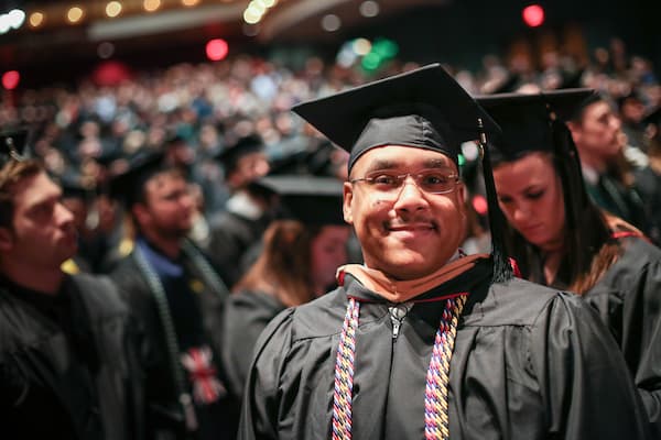 Male graduate smiles for photo at comencement ceremony