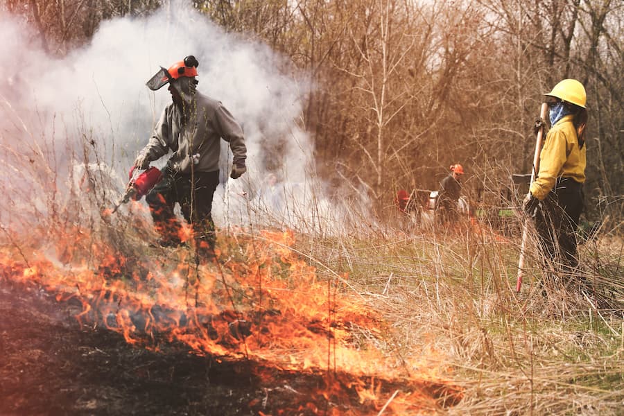 Students in protective gear perform prairie burn