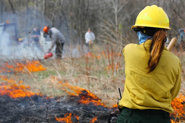 Students in protective gear preform prairie burn