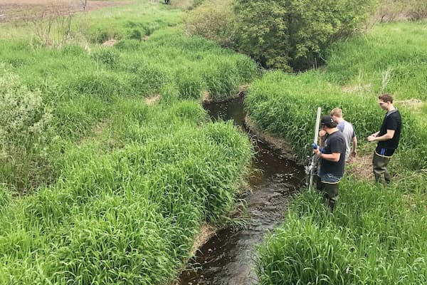 Students set up equipment in creek to test water