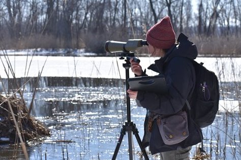 Researcher looking through a telescope over a frozen pond