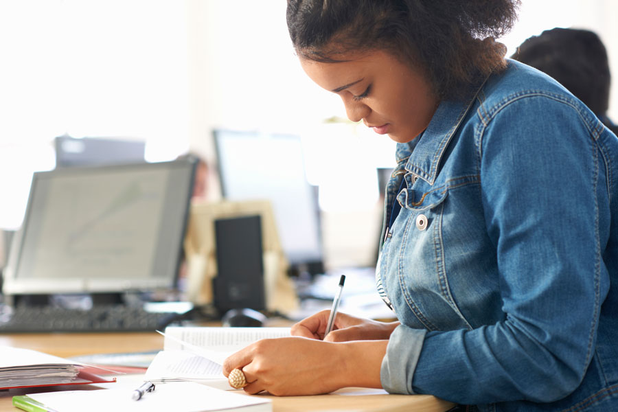 African American female takes notes in class