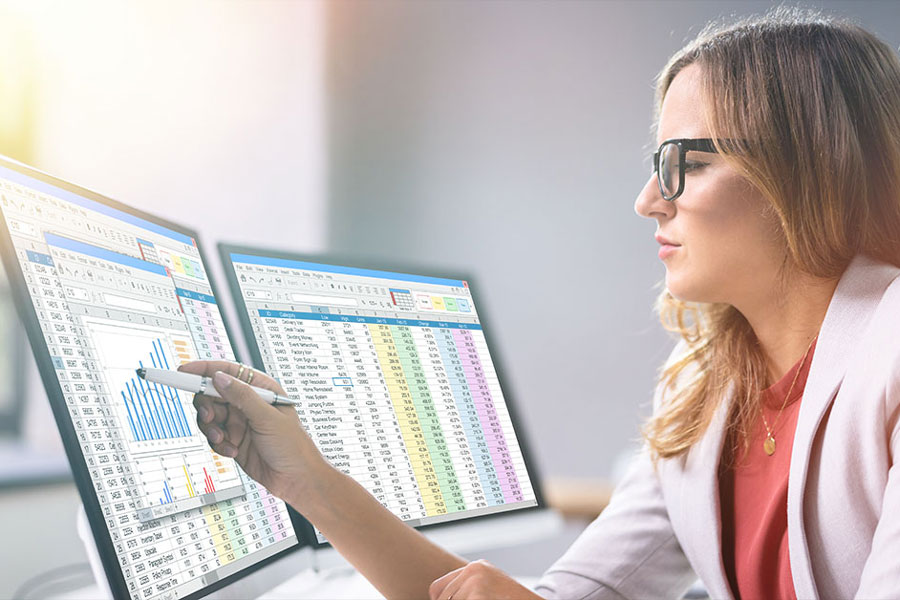 Female looks at data science on dual monitors