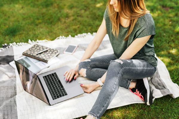 Student sits outside while studying on laptop