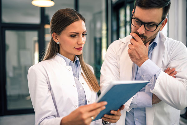 Male and female workers look of patient chart