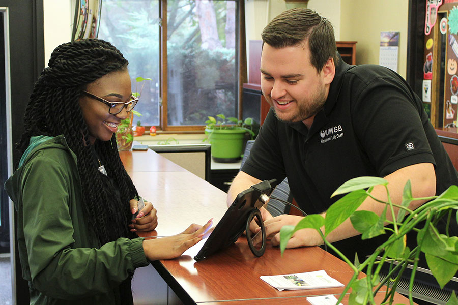 A front desk staff helping a student inside the community center