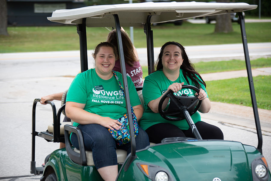 Housing staff riding a golf cart as they work at move-in day