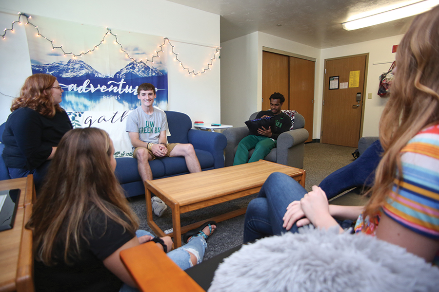 Students sitting in their apartment living space.