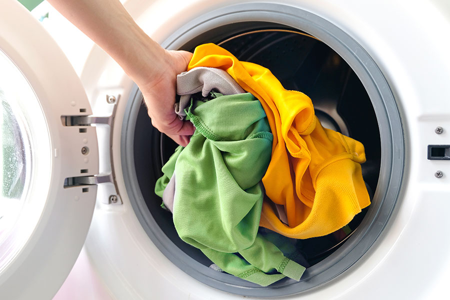 putting clothes into a laundry machine