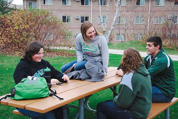 Students on a picnic table outside of the apartments