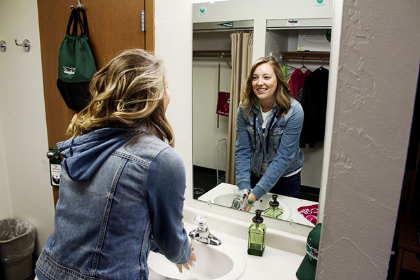Student washing her hands at a private sink in a uwgb dorm room