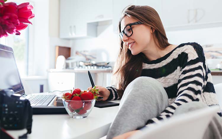 Online student working on a laptop in her kitchen