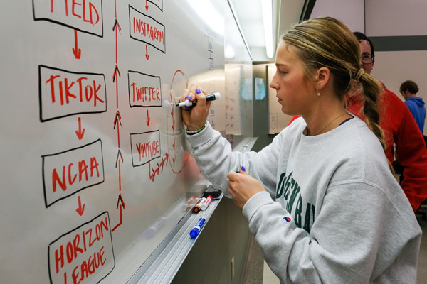Female student writes on white board