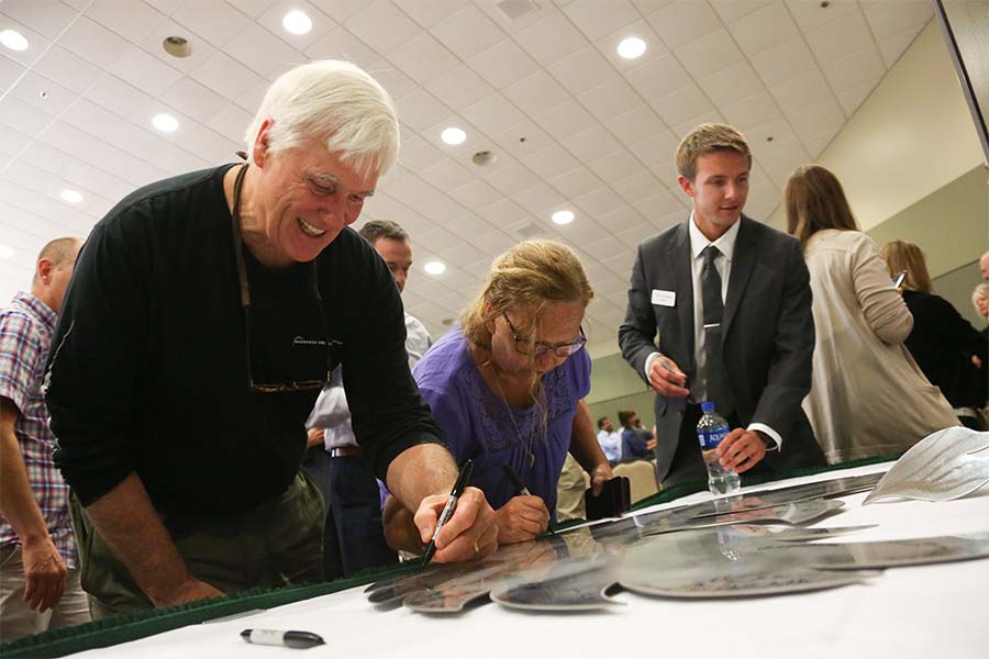 Faculty and staff signing their committment to the rise on the stainless steel phoenix emblem