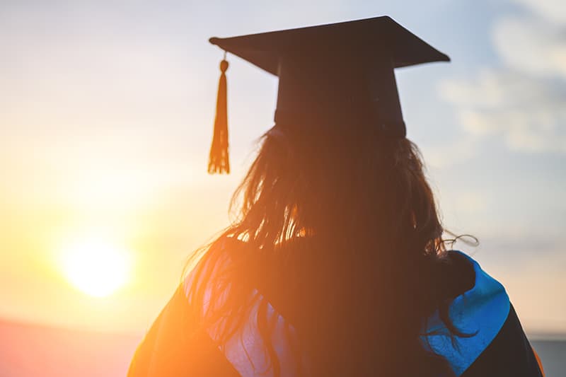 Image of graduating student against sunrise