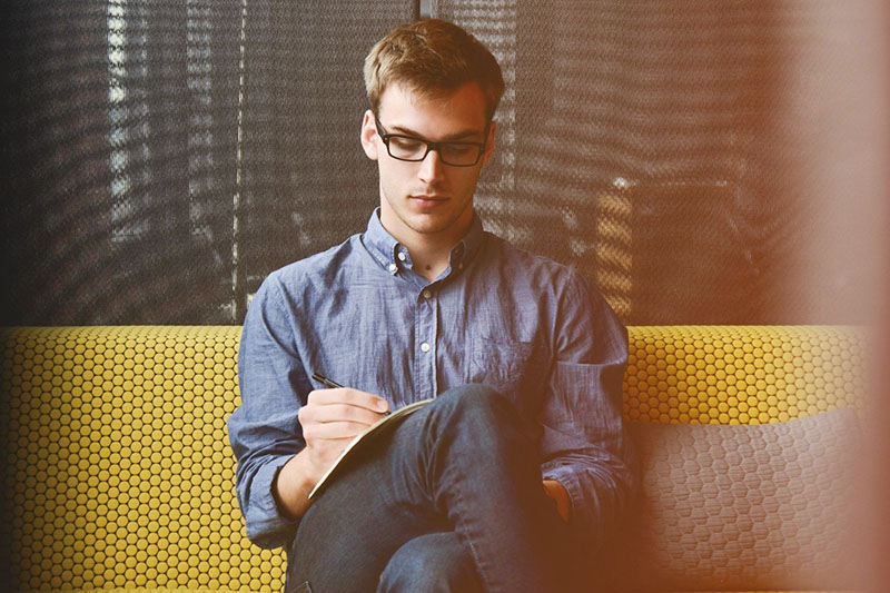 Man sitting taking notes in a notebook