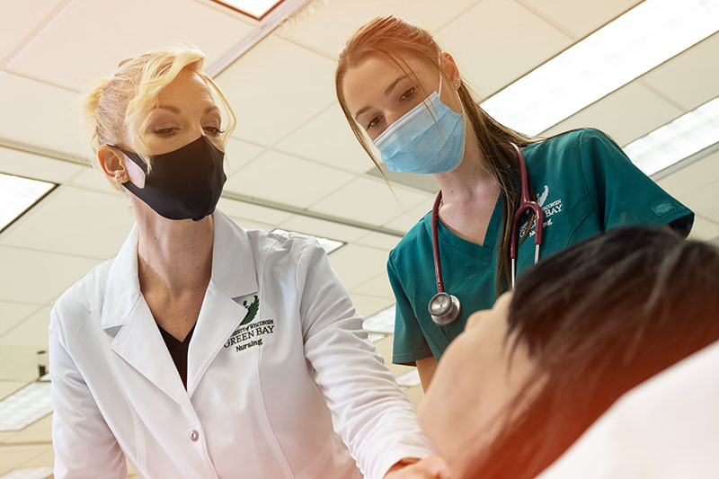 Student working with professor in nursing sim lab