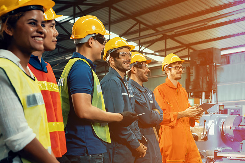 Workers attending brief meeting wearing hard hats and vests