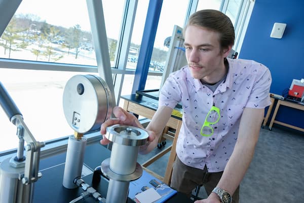 Male student in stem center works with engineering lab simulation equipment
