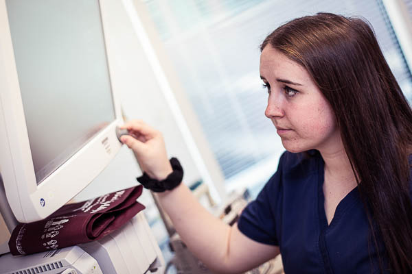 Nursing student adjusting monitor knob.