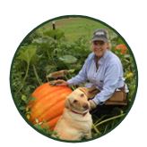 Deb Pearson with a dog next to a large pumpkin