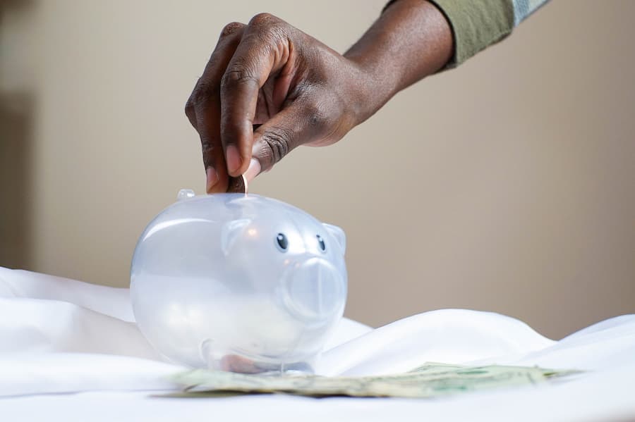 Hand puts coins in piggy bank