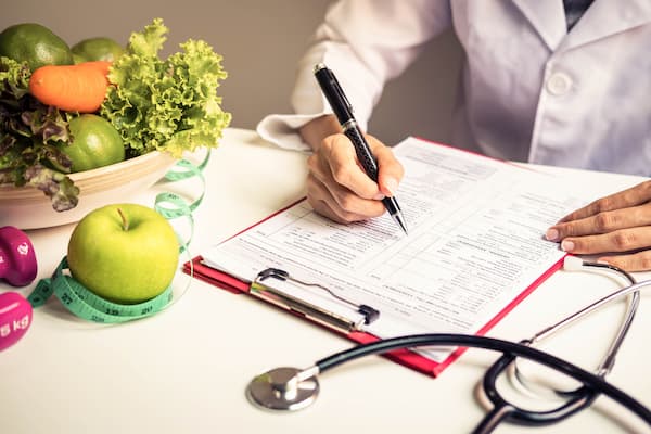 Dietition working on nutrition plan with bowl of fruits and veggies