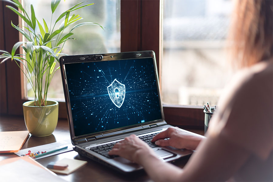 Woman working on a laptop with a cybersecurity screen