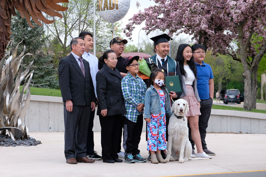 Asian graduate poses with family at commencement