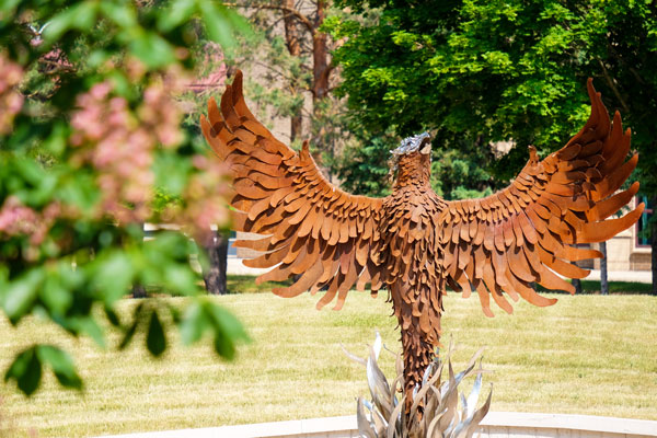 UW-Green Bay student poses in front of Pheonix Sculpture