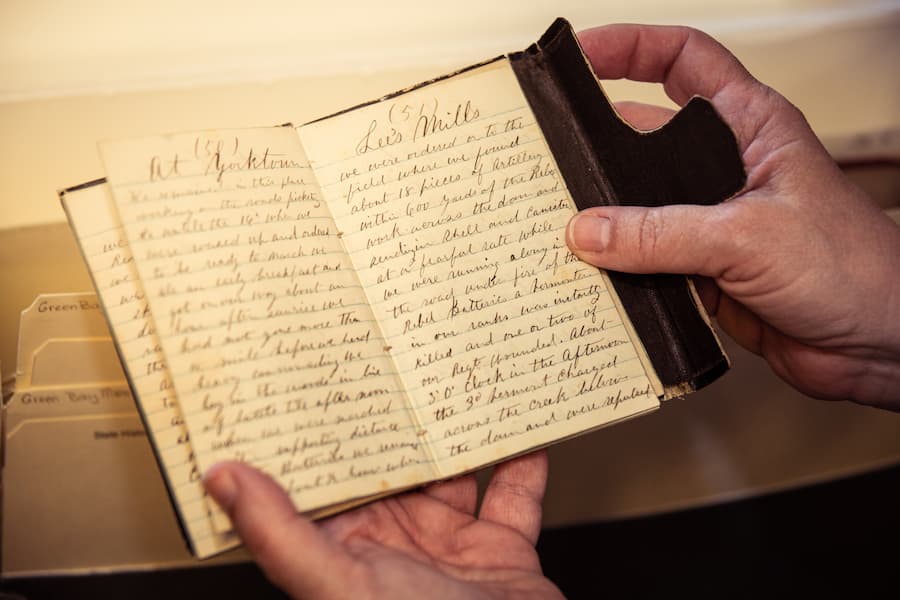 Hands holding a diary artifact from the archives, primary source document