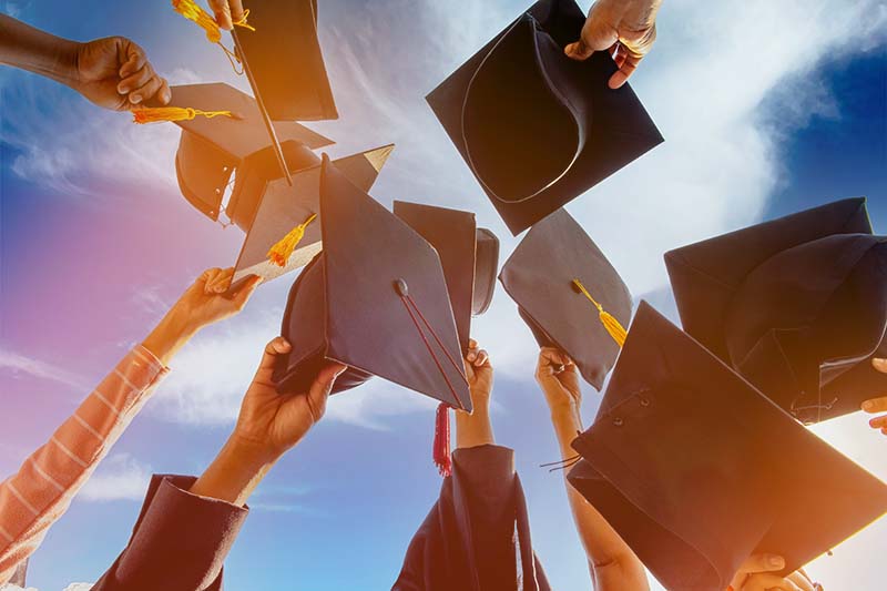 graduates holding their caps