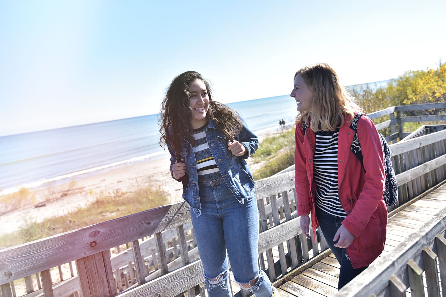 Two students walking outdoors along Lake Michigan boardwalk