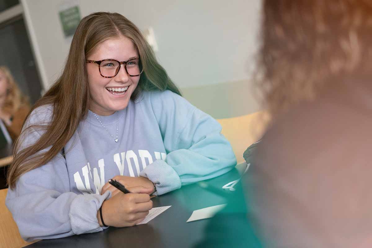 Rising Phoenix student sitting at a table smiling