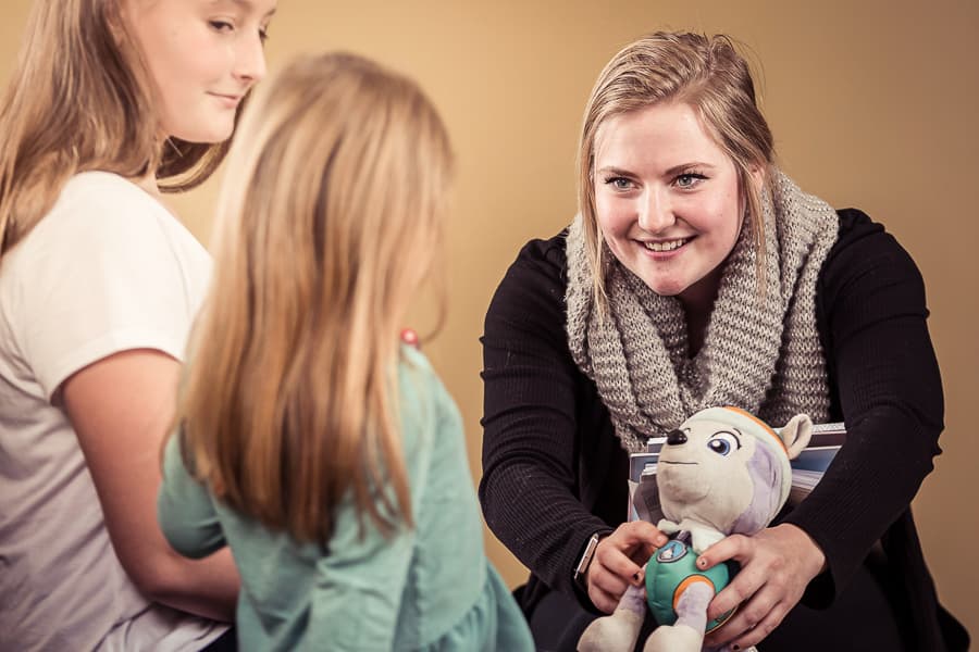 Social work professional give stuffed animal to child