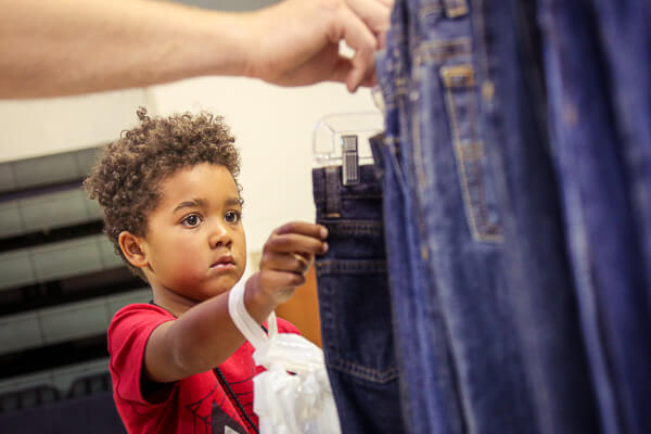 Volunteer helping a child pick out jeans at the Back to School Store at UWGB