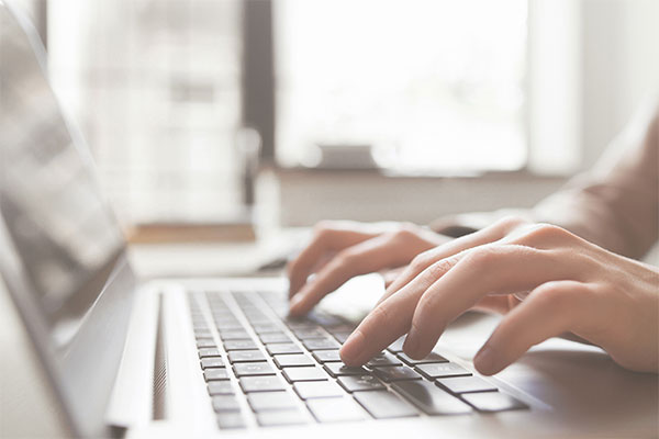 Hands typing up a résumé on a laptop