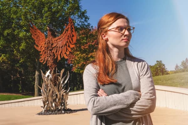 UW-Green Bay student poses in front of Pheonix sculpture