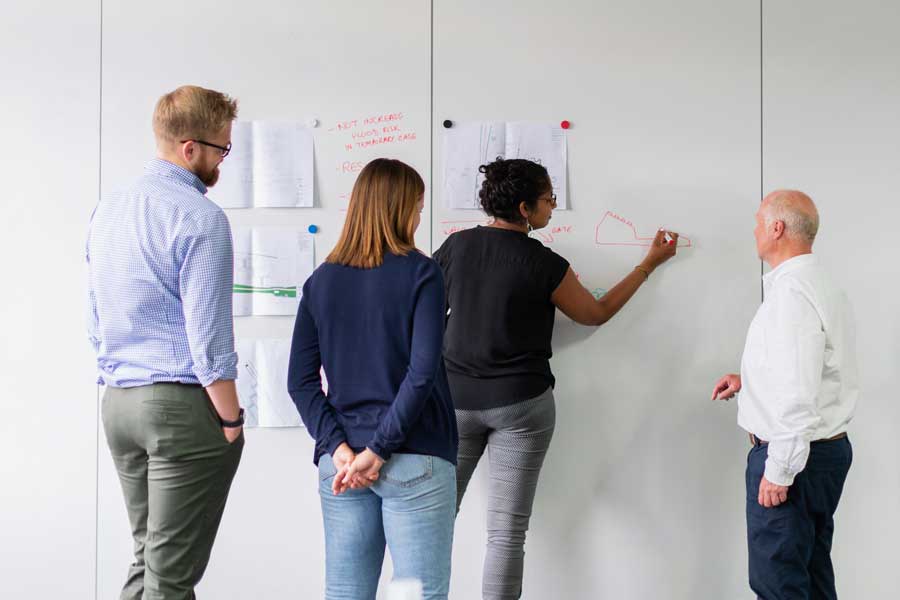 Group of coworkers brainstorm at white board